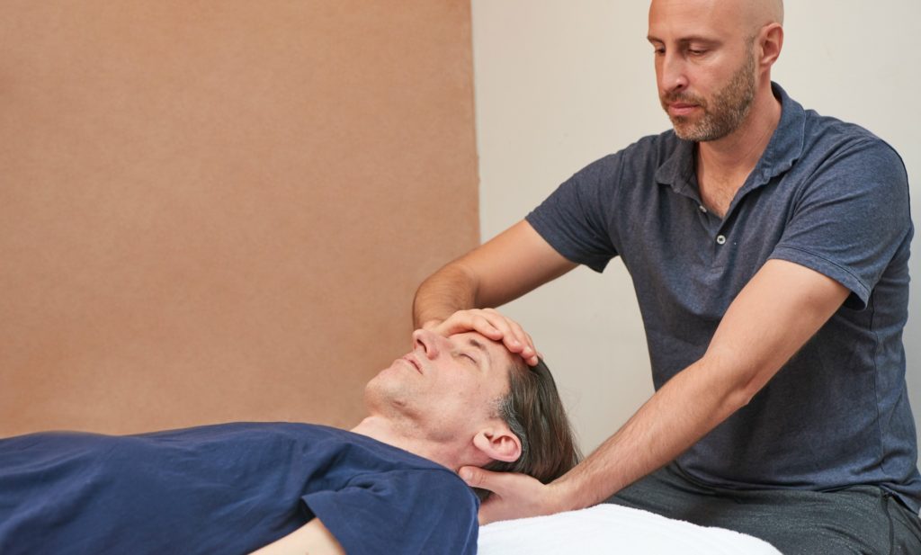 man receiving craniosacral therapy treatments at triyoga