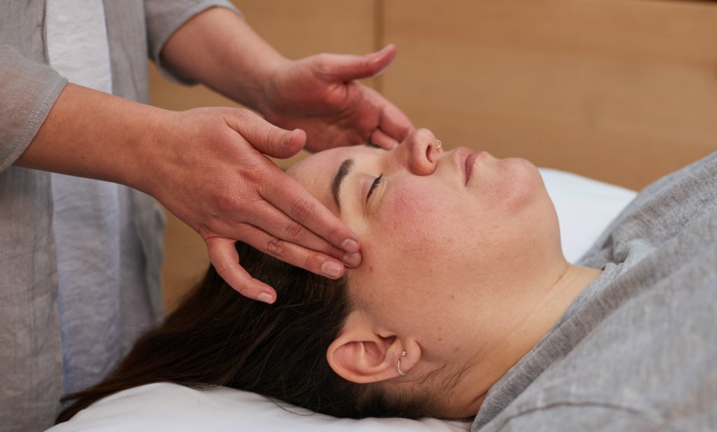 woman receiving a facial massage treatment at triyoga