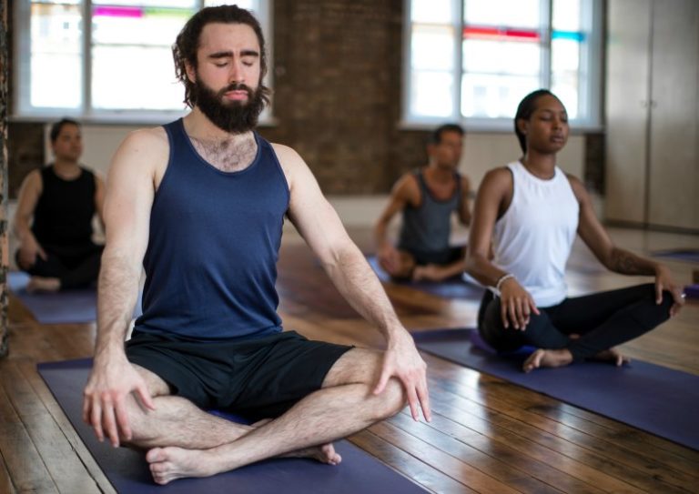 man meditating in yoga class triyoga