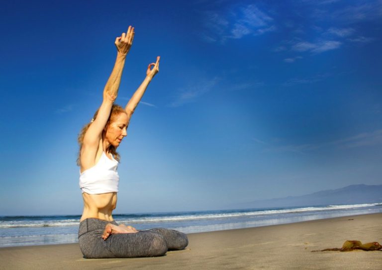 women seated yoga posture on beach Annie Carpenter triyoga