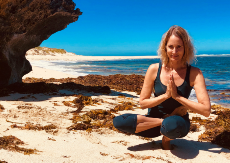 woman doing seated yoga pose on sunny beach, Sarah Powers self-exploration triyoga