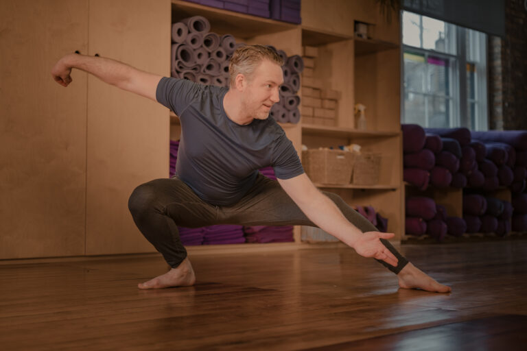 man doing qigong pose in a yoga studio