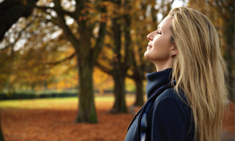 woman looking upward at autumn trees