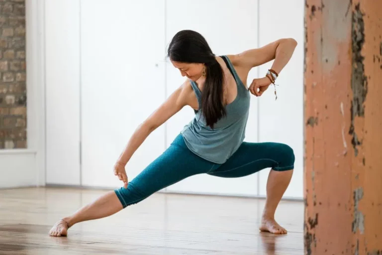 Mimi, a Qigong yoga practitioner, is doing a pose perfectly in a Triyoga studio in London. She is focused and relaxed, and her face is serene.