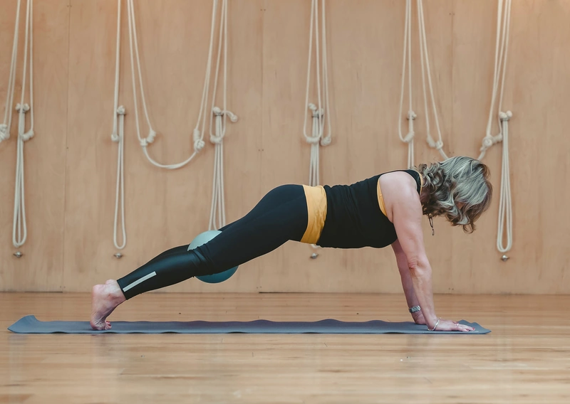Woman performing plank exercise on mat.