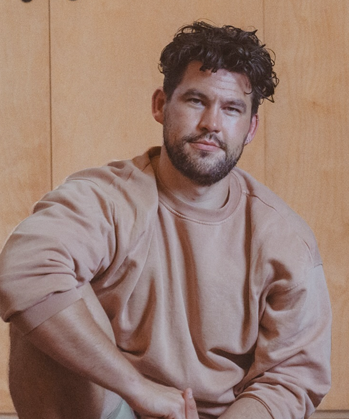 Man seated, casual attire, relaxed expression.