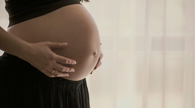 Pregnant woman gently touching belly.
